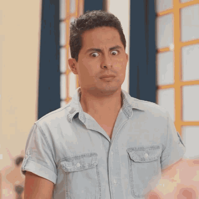 a man in a denim shirt makes a surprised face