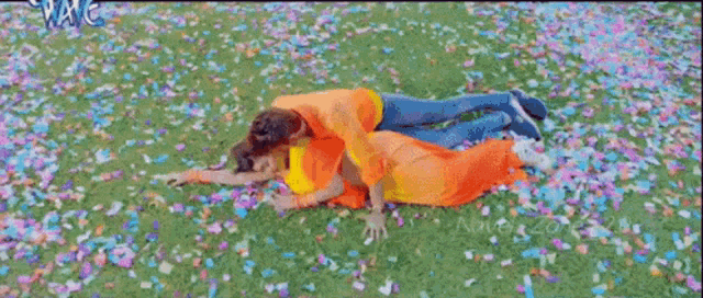 a man and a woman are laying on the ground in a field of flowers .