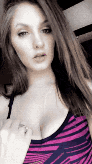 a woman wearing a zebra print tank top is taking a selfie with her phone