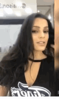 a woman with long dark hair is wearing a black t-shirt with a choker .