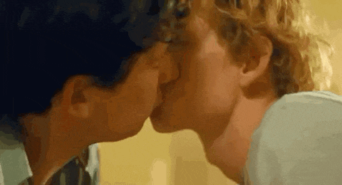 a close up of two men kissing each other on the cheek .