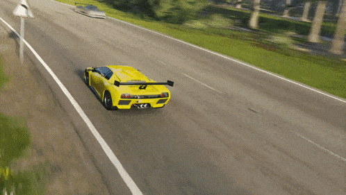 a yellow sports car is driving down a road next to a red and white triangle sign