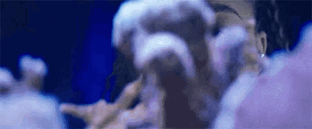 a close up of a person 's face in a blurry photo with a purple background .