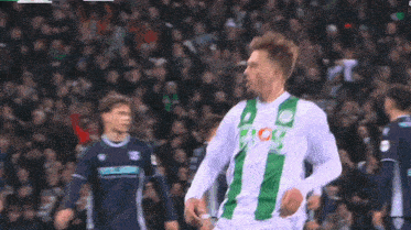 a soccer player wearing a green and white jersey with the letters cg on the front
