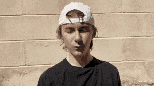 a young man wearing a white baseball cap and a black shirt