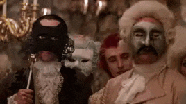a group of people are wearing masks and wigs at a masquerade ball .
