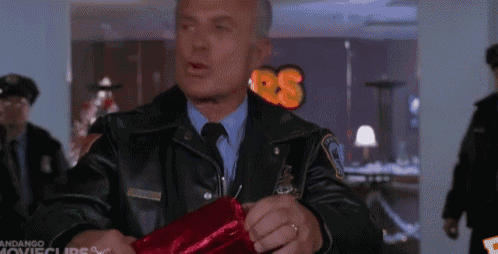 a man in a police uniform is holding a red item in his hand .