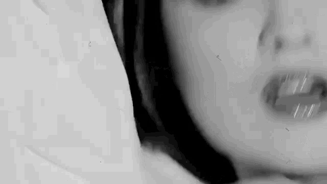 a close up of a woman 's face in a black and white photo with her mouth open .