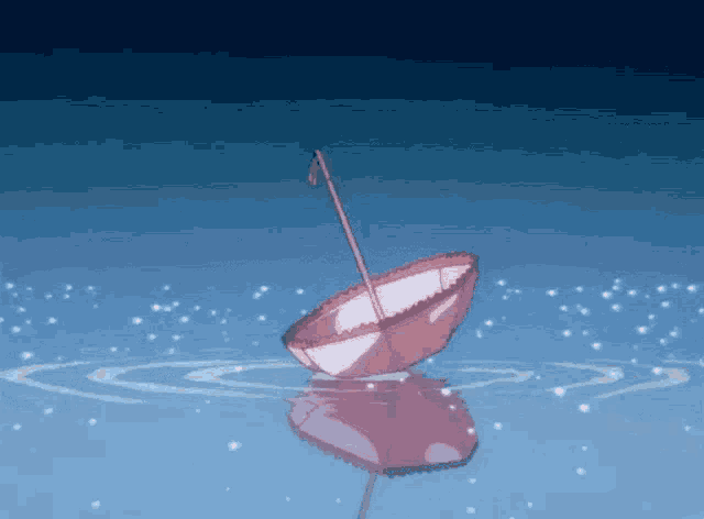 a pink umbrella is floating in the water with snow falling