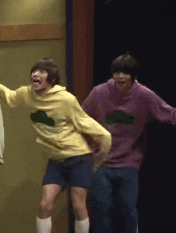 a couple of people are standing next to each other on a stage . one of the people is wearing a purple sweater .