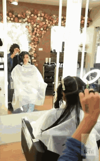 a woman is getting her hair cut in a salon while sitting in a chair .