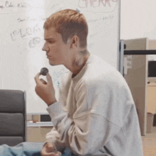 a man is eating a cherry in front of a white board that says cherry