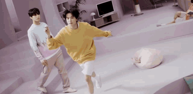 a man in a yellow sweater and white shorts is running in a room