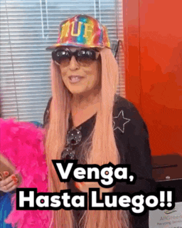 a woman wearing a hat sunglasses and a pink boa says venga hasta luego !
