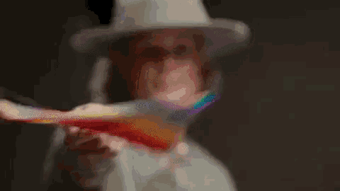 a man in a hat is holding a rainbow flag in his hand .