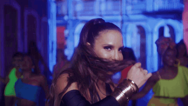 a woman with a ponytail is smiling in front of a crowd of people