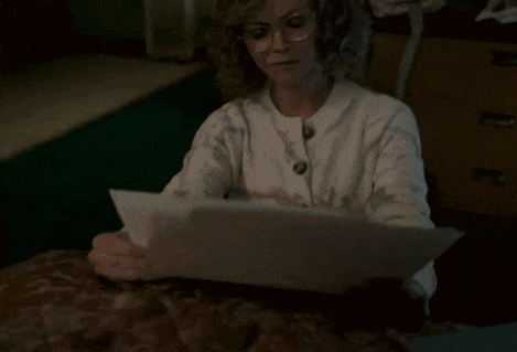 a woman in a white sweater is holding a piece of paper
