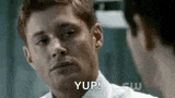 a man in a white shirt is looking at another man in a mirror and saying yup .