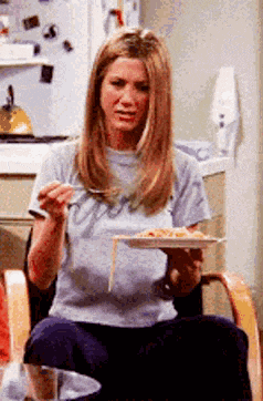 a woman is sitting in a chair eating a plate of spaghetti with a fork
