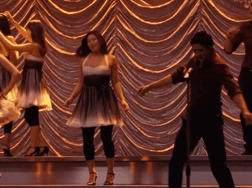 a group of people are dancing in front of a curtain