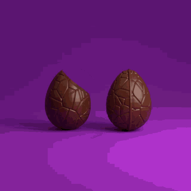 two chocolate eggs are sitting on a purple background
