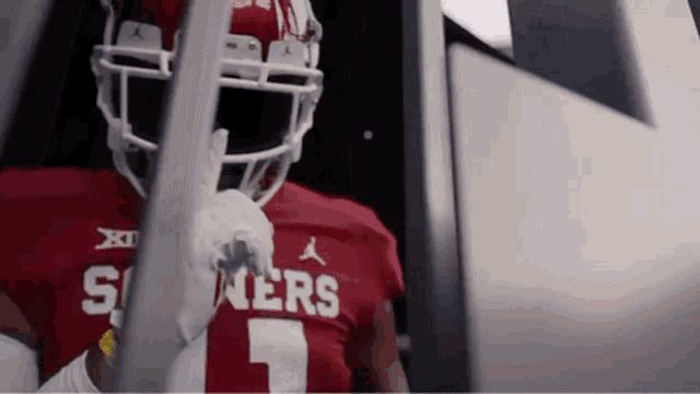 a football player wearing a red jersey and white helmet is standing in a locker room .