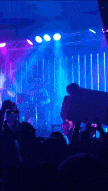 a group of people taking pictures of a band on stage with a sign that says " i love you "