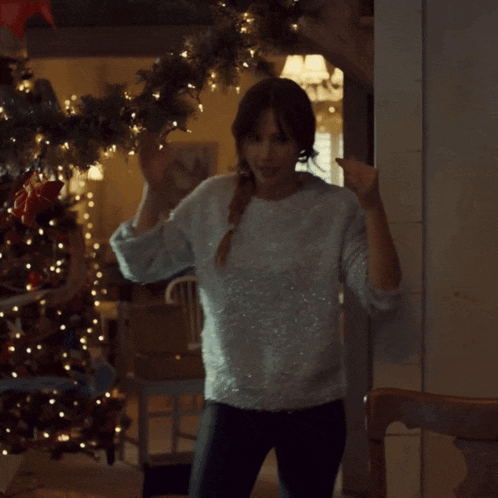 a woman standing in front of a christmas tree