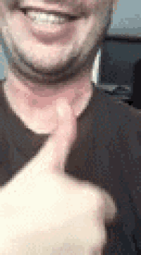 a close up of a man giving a thumbs up .