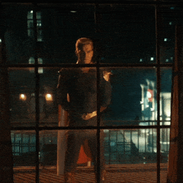 a man in a superhero costume looks out of a window at night