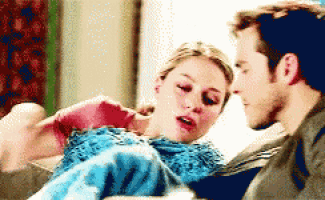 a man and a woman are sitting next to each other on a couch and looking at each other .