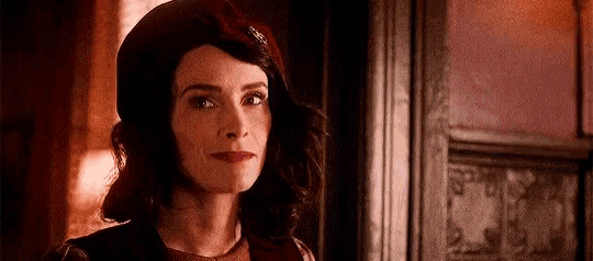a woman wearing a red hat and a red dress is standing in front of a door .