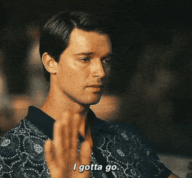 a man in a blue shirt is saying `` i gotta go '' with his hand .