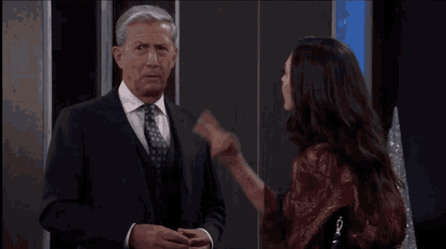 a man in a suit and tie stands next to a woman who is pointing at him