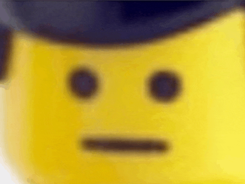 a close up of a yellow lego man 's face with a hat on .