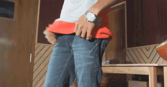 a man with a watch on his wrist is standing in front of a wooden table