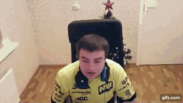 a man wearing headphones and a hyperx shirt is sitting in a chair