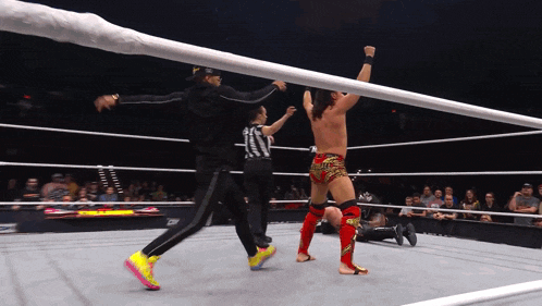 a man in a wrestling ring with a referee and a wrestler wearing a pair of pink nike shoes