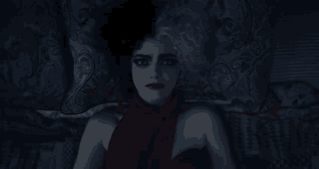 a woman in a red dress is laying down in the dark