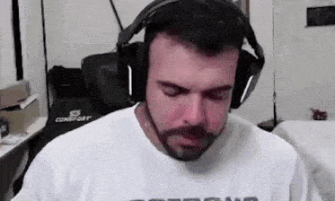 a man with a beard wearing headphones and a white shirt .
