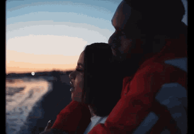 a man and a woman are hugging each other and looking at the ocean