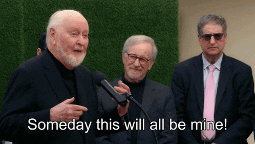a man speaking into a microphone with someday this will all be mine written below him