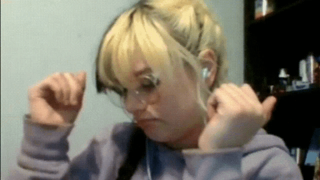 a woman wearing glasses and ear buds looks at the camera