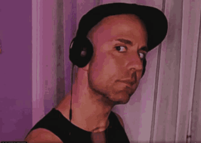 a man wearing headphones and a baseball cap looks at the camera