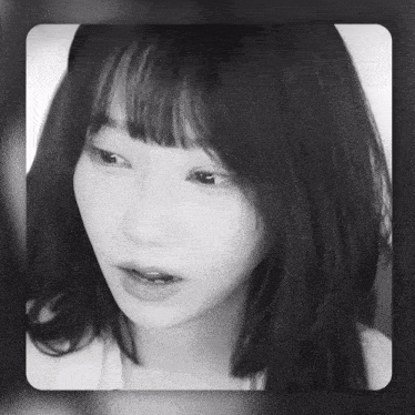 a black and white photo of a woman 's face with bangs