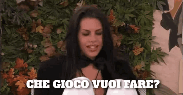a woman says che gioco vuoi fare in front of a wall of leaves .