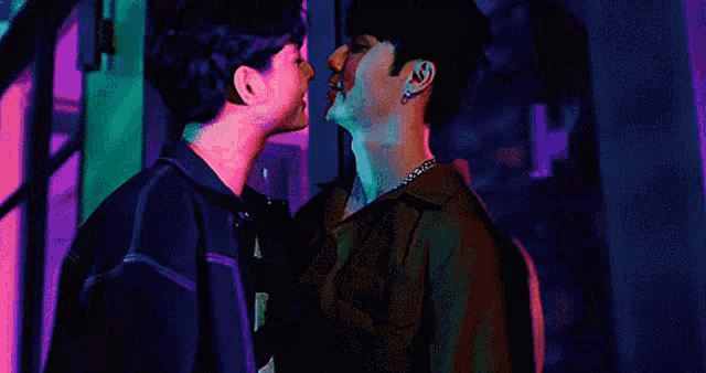 a couple of men are standing next to each other and kissing .
