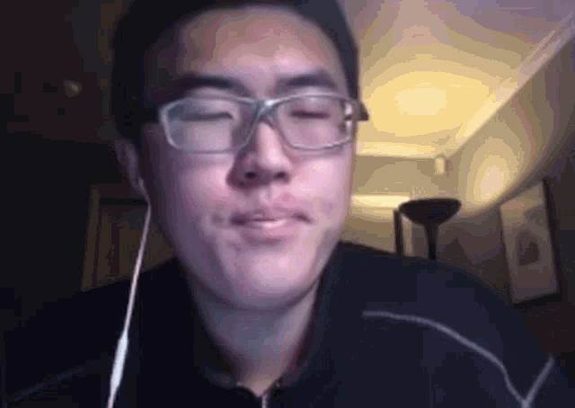 a man wearing glasses and ear buds is making a funny face