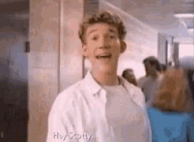 a young man in a white shirt is standing in a hallway with a group of people .