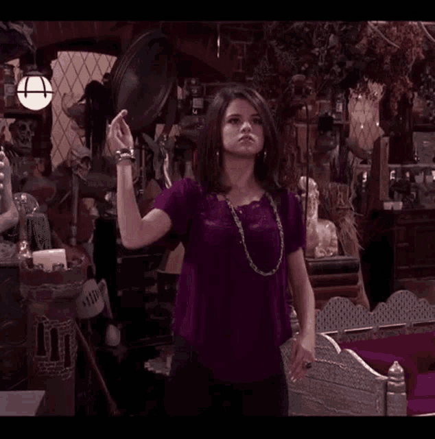 a woman in a purple shirt is standing in a room holding a broom .